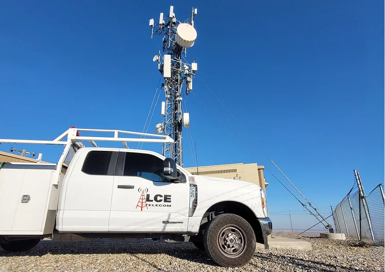 LCE Telecom service vehicle parked at a wireless cell site with a telecommunications tower and antenna equipment in the background.