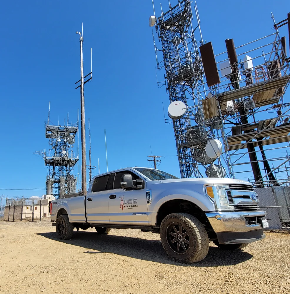 LCE Telecom service truck parked at a telecommunications cell tower site equipped with antennas and network infrastructure.