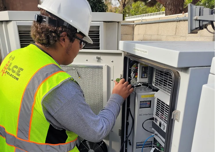 LCE Telecom field technician performing maintenance and testing inside an outdoor telecommunications network cabinet.