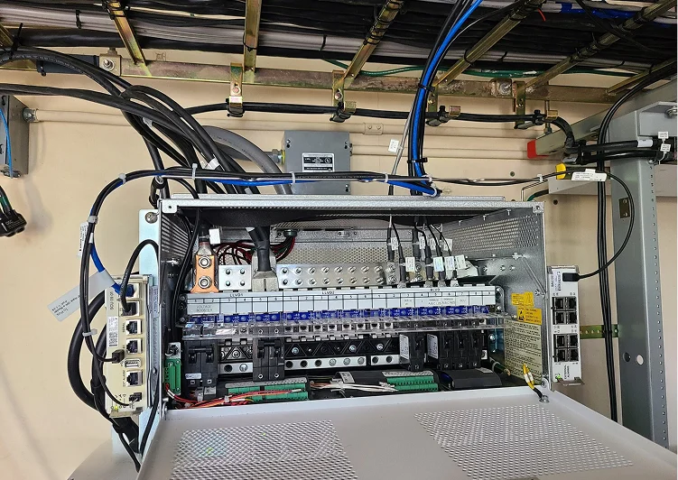 Telecommunications power distribution panel with organized cabling, circuit protection, and network equipment inside an equipment cabinet.