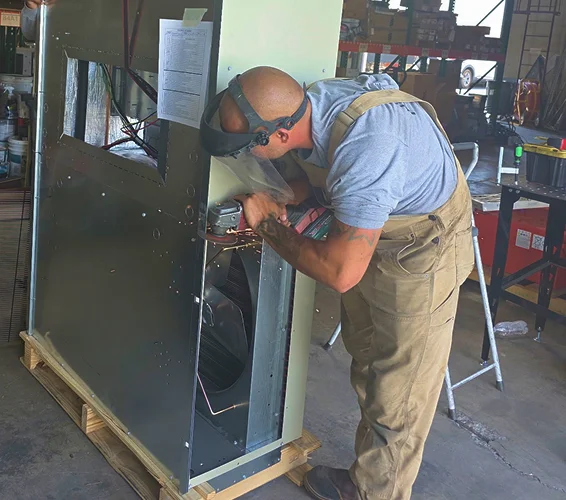 LCE Telecom technician installing and servicing HVAC equipment inside a telecommunications facility.