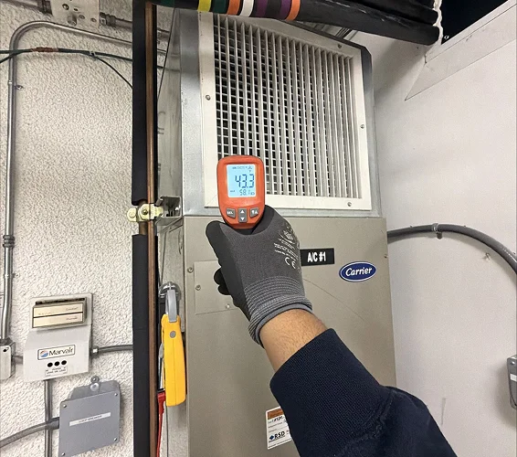 LCE Telecom technician measuring temperature on an HVAC unit at a telecommunications facility.